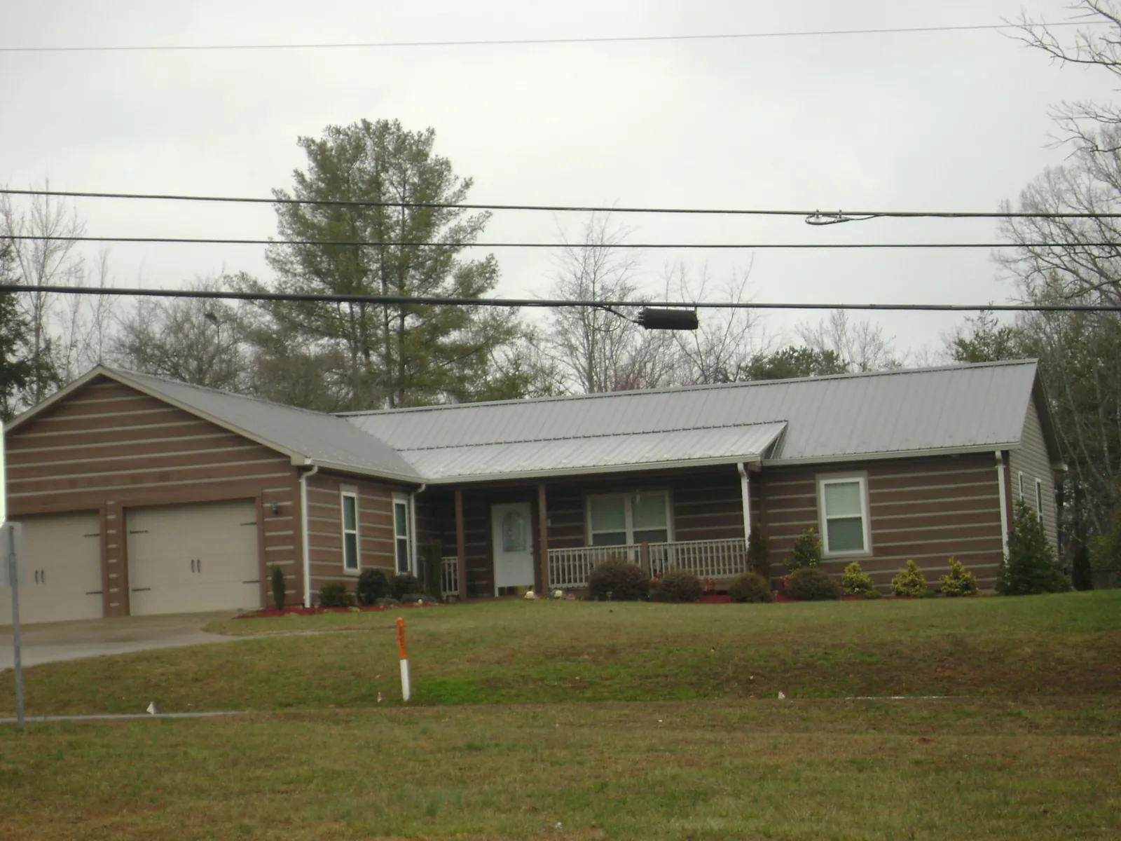 Gray metal roof on a log sided ranch home with a front porch in Hamilton